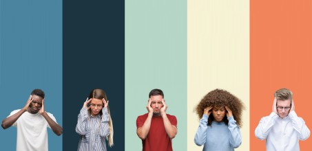 Fünf Personen die sich an den Kopf fassen. Das Gesichtist schmerzverzerrt und der Kopf ist nach unten geneigt.